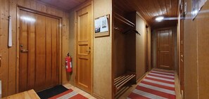 A hallway with wooden doors, a fire extinguisher, and a red and white striped carpet.