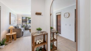 En modern inredning med trägolv, en soffa, ett soffbord, en lampa, en spegel och en klocka på väggen.