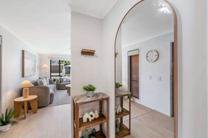 Ein modernes Interieur mit Holzboden, einer Couch, einem Couchtisch, einer Lampe, einem Spiegel und einer Wanduhr.