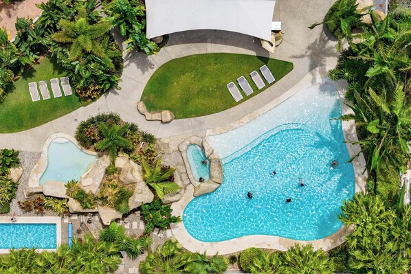 An aerial view of a resort with multiple swimming pools, lounge areas, and lush landscaping. - 3BR Ocean-view apartment at Mirage Resort (Alexandra Headland)