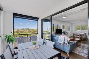 Ein Balkon mit Tisch und Stühlen, eine Sitzecke und ein Fernseher im Wohnbereich.
