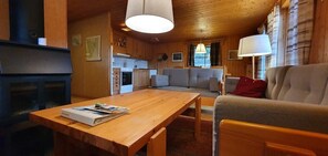 Ein gemütliches Blockhaus-Interieur mit Holztisch, Sofa und Kamin.