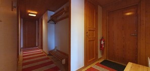 A hallway with a wooden door, a fire extinguisher, and a red carpet. - Sauna | Wi-Fi | Terrace | Wood stove | Cable TV (Lofsdalen)