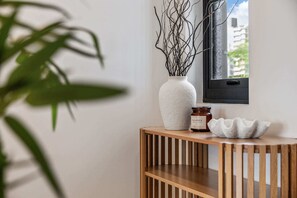 Ein Holzkonsolentisch mit einer weißen Vase, gefüllt mit Zweigen, einem mit 'BALANCE' beschrifteten Glas und einer strukturierten weißen Schale.