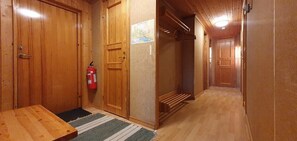 Ein Innenkorridor mit Holzboden, einem Feuerlöscher, einem Holztisch und einem Teppich.