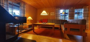 A cozy living room with a sofa, a coffee table, a television, and a lamp. - Sauna | Wi-Fi | Terrace | Wood stove | Cable TV (Lofsdalen)