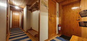 Ein Korridor mit Holztüren, einem blauen Streifen Teppich und einer hölzernen Bank.