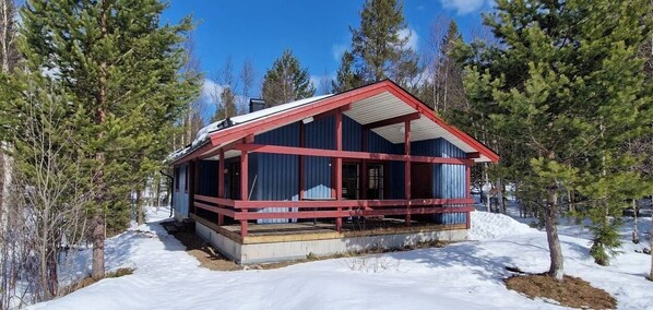 Eine Hütte mit roter Fassade, großen Fenstern und einer überdachten Veranda.