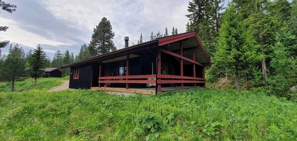 Eine Holzhütte mit einer Holzterrasse, umgeben von Wald.