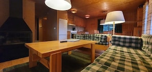 Ein gemütliches Blockhäuschen-Interieur mit einem Holzespeisetisch, einem karierten Sofa und einem Kamin.