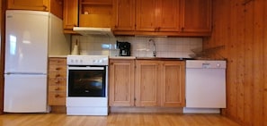 Eine Küche mit Holzschränken, einem weißen Kühlschrank, einem Herd, einem Backofen und einem Geschirrspüler.
