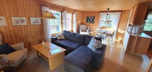 Ein Interieur einer Holzhütte mit einer Couch, einem Tisch und einem Stuhl.