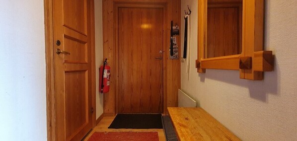 Eine Holztür mit Feuerlöscher, einer schwarzen Fußmatte und einem Holztisch.