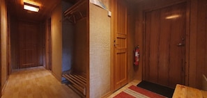 Ein Flur mit Holztüren, einem Feuerlöscher und einer roten Fußmatte.