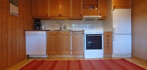 Eine Küche mit Holzausstattung, einem weißen Geschirrspüler, einem Herd und einem Kühlschrank.