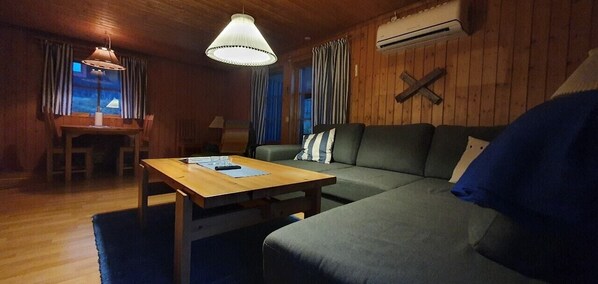 Ein gemütliches Zimmer mit Holzboden, einer Couch, einem Tisch und einer Pendelleuchte.