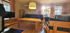 Ein Wohnzimmer mit Holztisch, Sofas, Fernseher und Bücherregal.