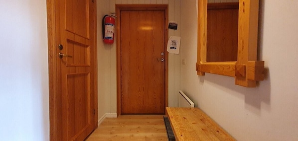 Eine Holztür, ein Feuerlöscher, ein QR-Code und ein Fensterrahmen.