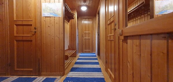 Ein Holzboden-Flur mit einem blau-weißen Streifen Teppich, Holztüren und einer Sitzbank.