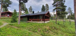 Eine Hütte mit Veranda, umgeben von Bäumen und einer Wiese.