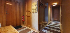 Ein Holzboden-Flur mit einem Feuerlöscher, einem Streifen Teppich und einer Tür mit einem gemusterten Vorhang.