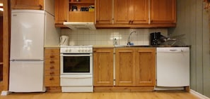 Eine kleine Küche mit Holzausstattung, einem weißen Kühlschrank, einem Herd, einer Spüle und einem Geschirrspüler.