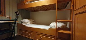 A bunk bed with a desk and drawers, a lamp, and a mirror.