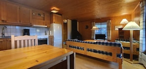 Ein Holzinterieur mit einer Küche, einem Esstisch und zwei Betten mit karierter Bettwäsche.