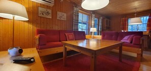 Ein Holzinnenraum mit einem roten Sofa, einem Holztisch und einer Lampe.