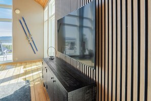A modern living room with a large flat-screen TV, wooden slat wall, and a ski rack. - Ski-in/out | Pool table | Sauna | BBQ grill | WiFi (Lofsdalen)