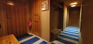 Ein Flur mit einer Holztür, einem Feuerlöscher und einem blau gestreiften Teppich.