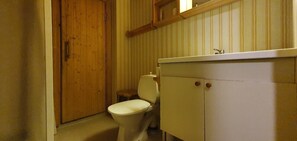 A small bathroom with a wooden door, a toilet, and a cabinet.