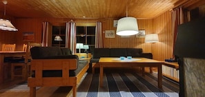 Ein Holzinnenraum mit einer Couch, einem Esstisch und einer Lampe.