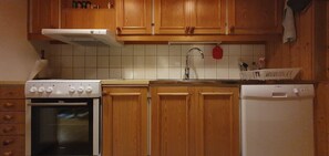 Eine Küche mit Holzausstattung, einem weißen Herd, einer Spüle und einem Geschirrspüler.
