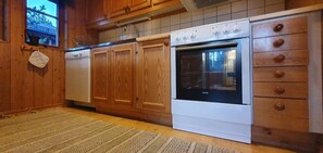 Eine Küche mit Holzschränken, einem Geschirrspüler und einem Backofen.
