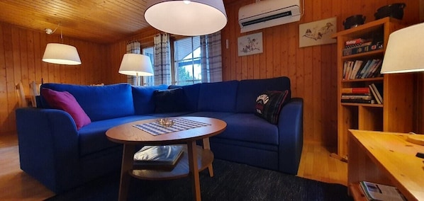 Ein gemütliches Zimmer mit einem blauen Sofa, einem runden Tisch und einem Bücherregal.
