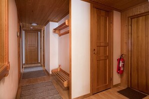 Un pasillo de madera con extintor, un banco y una puerta.