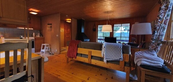 Ein gemütliches Blockhaus-Interieur mit einer hölzernen Bank, einer Couch, einem Esstisch und einer Lampe.