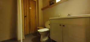 A bathroom with a toilet, wooden door, and a cabinet.