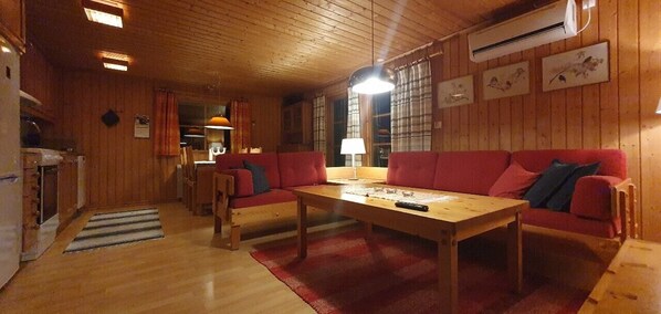 Ein Holzinterieur mit einer Couch, einem Tisch und einer Küchenzeile.