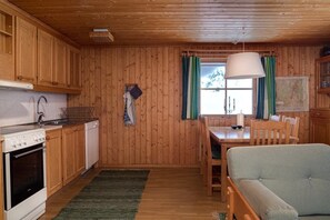 Ein Interieur einer Holzhütte mit Küche, Essbereich und einer Couch.