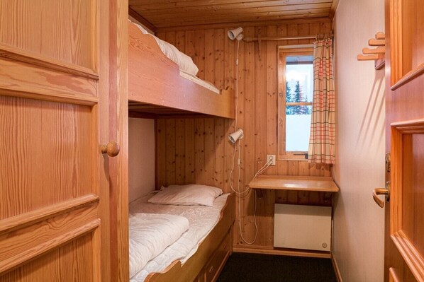 Ein kleines Zimmer in einer Holzhütte mit Etagenbetten, einem Fenster mit Aussicht und einem kleinen Schreibtisch.