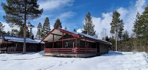 Eine Holzhütte mit rotem Dach, umgeben von Schnee und Bäumen.