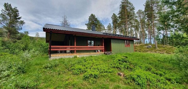 Eine Holzhütte mit Metalldach, einer Holzterrasse und einer kleinen Veranda.