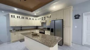 A kitchen with white cabinets, a granite countertop, and a stainless steel refrigerator.