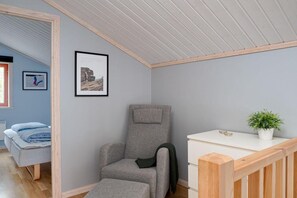 A room with a grey armchair, a white side table with a plant, and framed pictures on the wall. - Sauna | Ski-in/out | Wi-Fi | Ski shed | Wood stove (Lofsdalen)