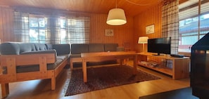 A wooden interior with a sofa, a table, a television, and a lamp. - Sauna | Wi-Fi | Terrace | Wood stove | Cable TV (Lofsdalen)