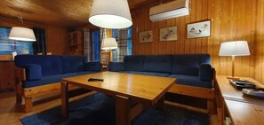 Una habitación con paneles de madera, un sofá azul y una mesa de centro de madera, además de una lámpara.