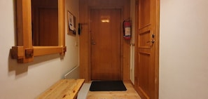 A wooden door with a fire extinguisher mounted on the wall to the right.