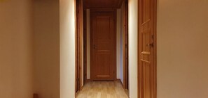 Un pasillo estrecho con puertas y piso de madera.